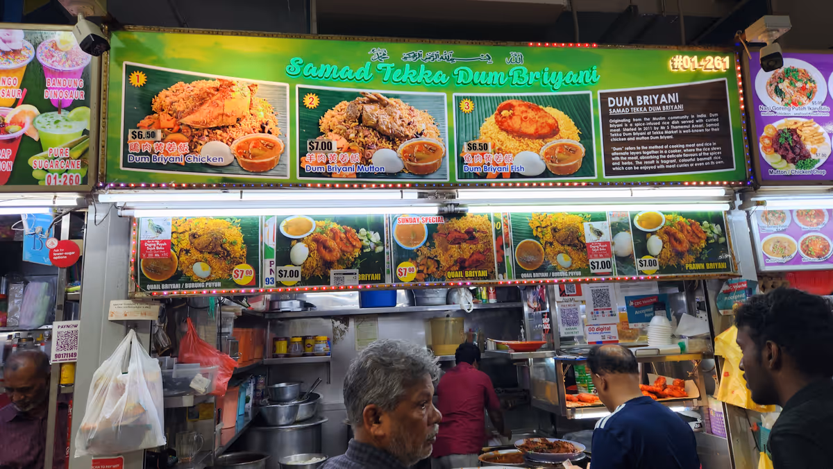 A biryani food stall with an overhead images of food in a various types.