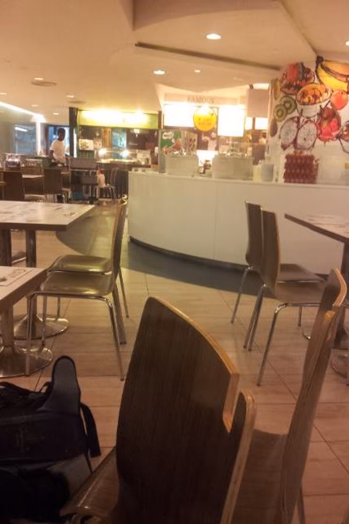 Chairs and tables in the food court with cashier counter behind.