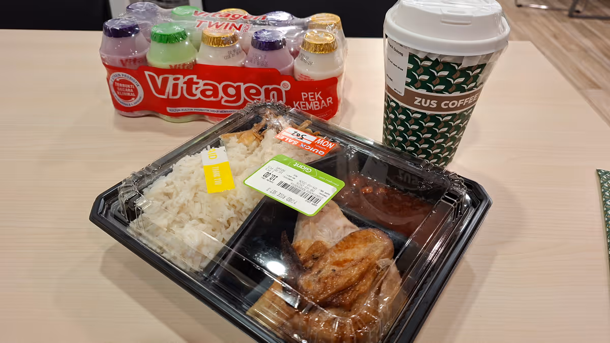 A lunchbox of chicken rice with a ZUS Coffee cup and a pack of probiotic milk behind it