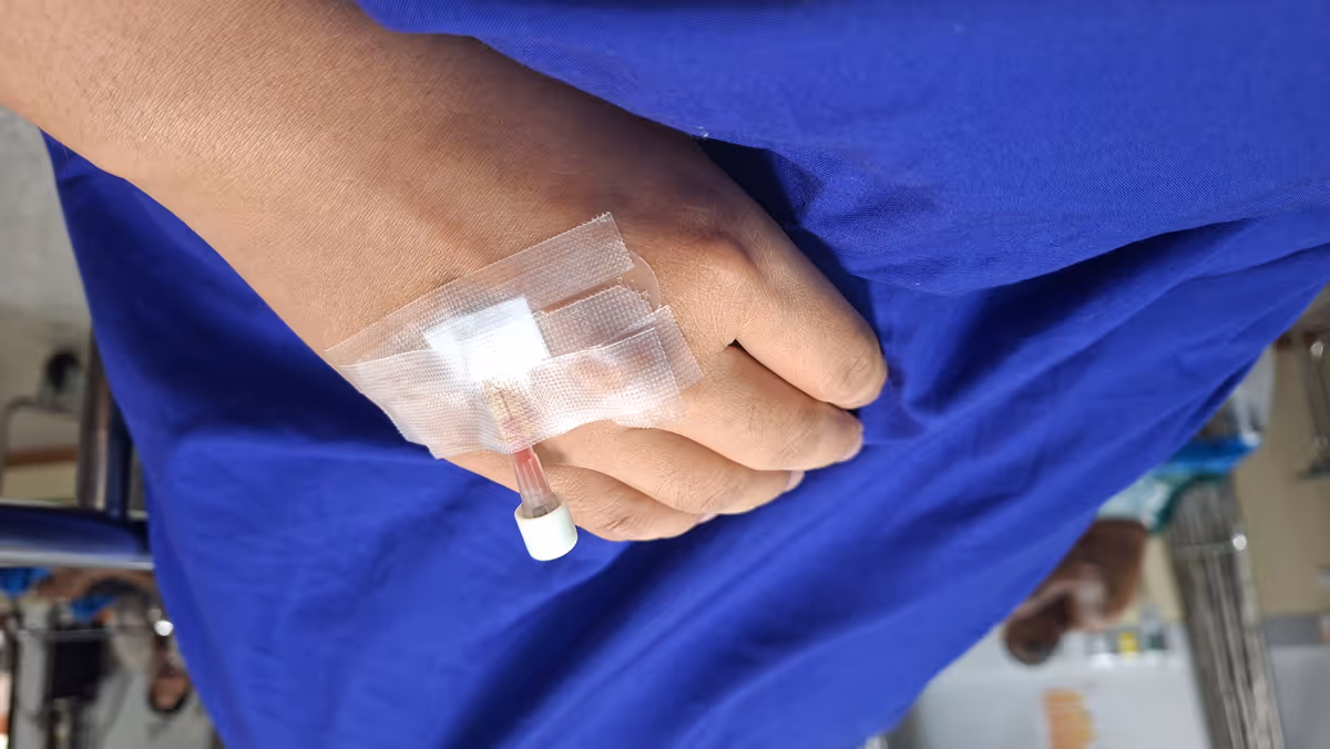 A hand with a medical injection with blue blanket