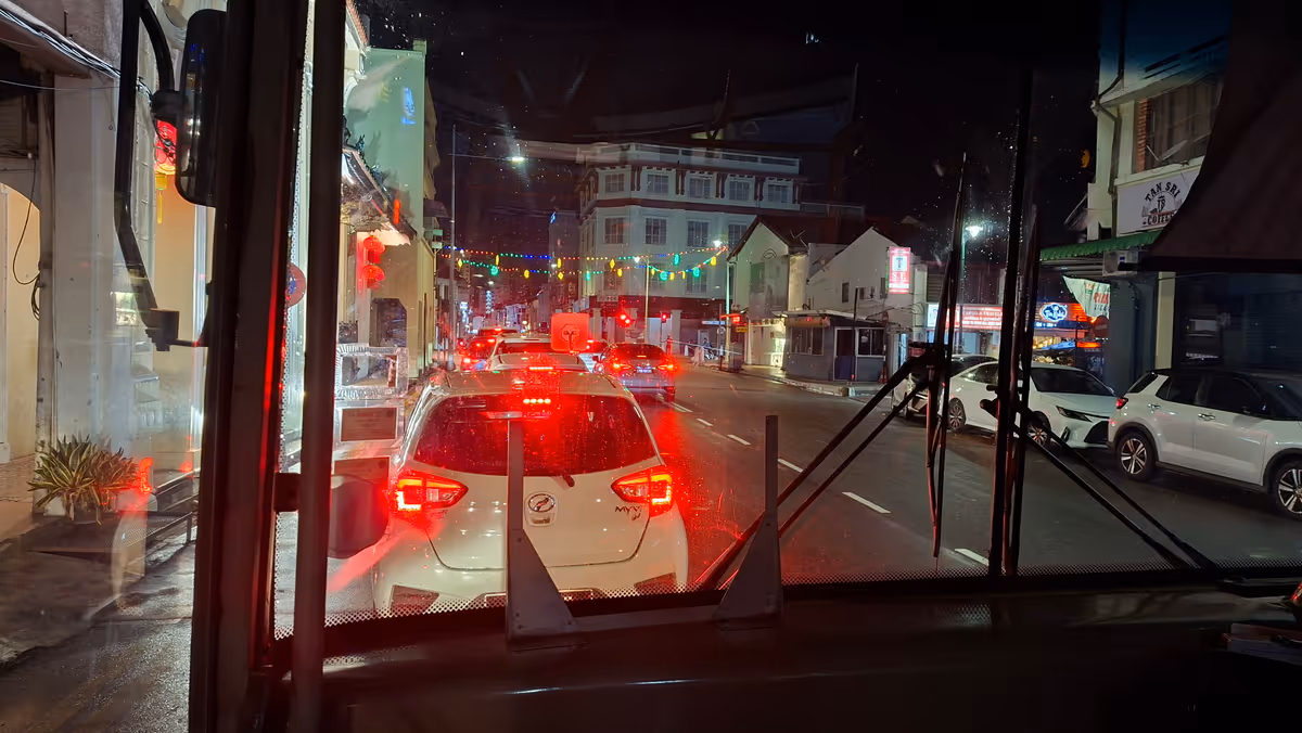 Cars stopped at a traffic light, seen through a bus windshield