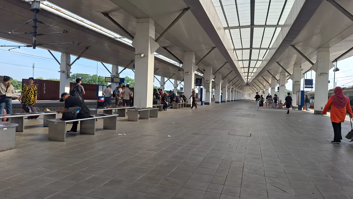 KTM Padang Besar train station with transparent cover. There are many people sitting on the floor.