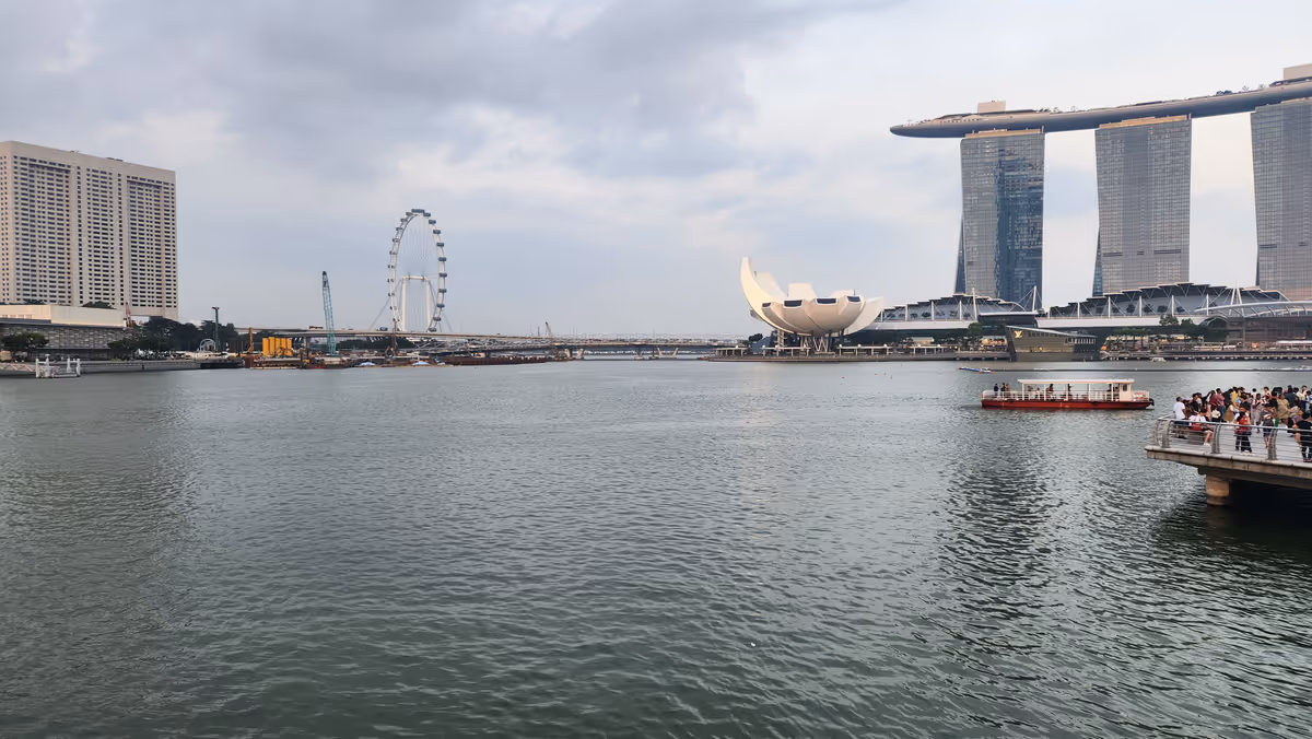 A bay and a three towers of Marina Bay Sands on the left and a Singapore Flyer.