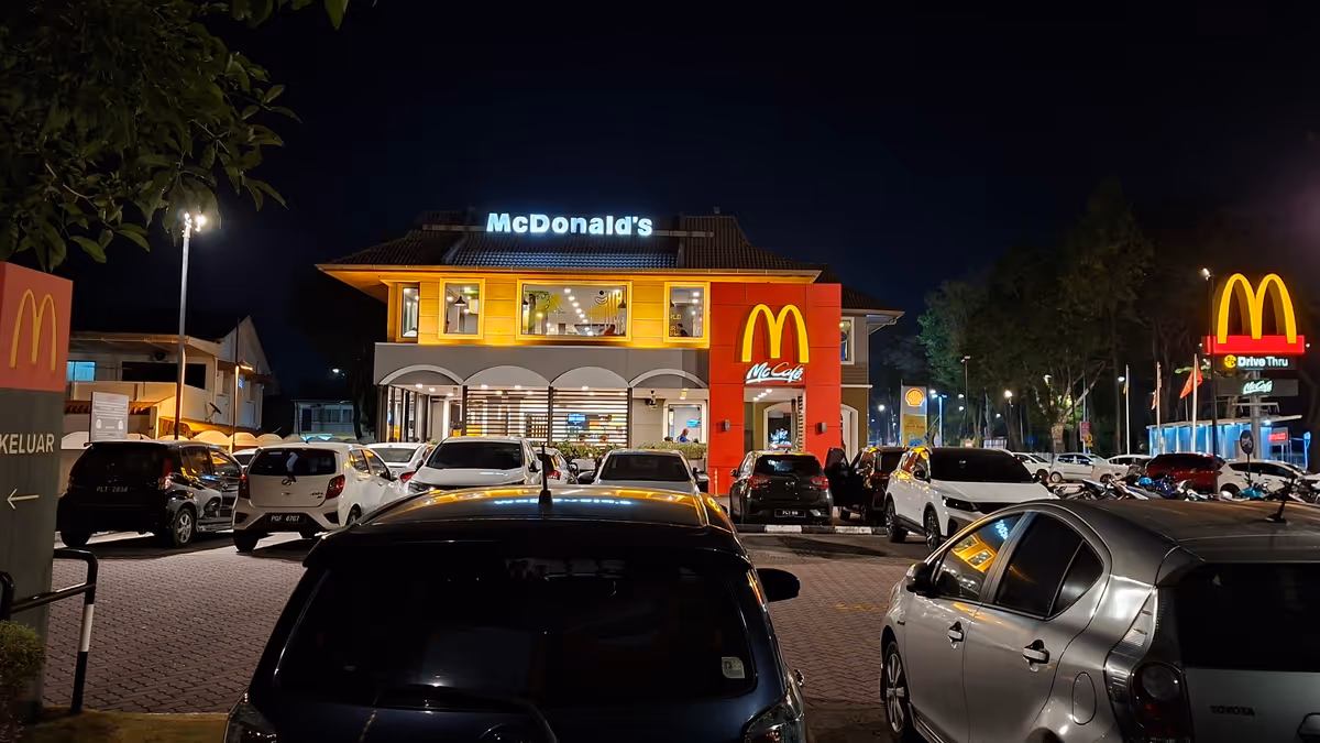 Cars parked in front of a McDonald's store at night with a large yellow neon M logo