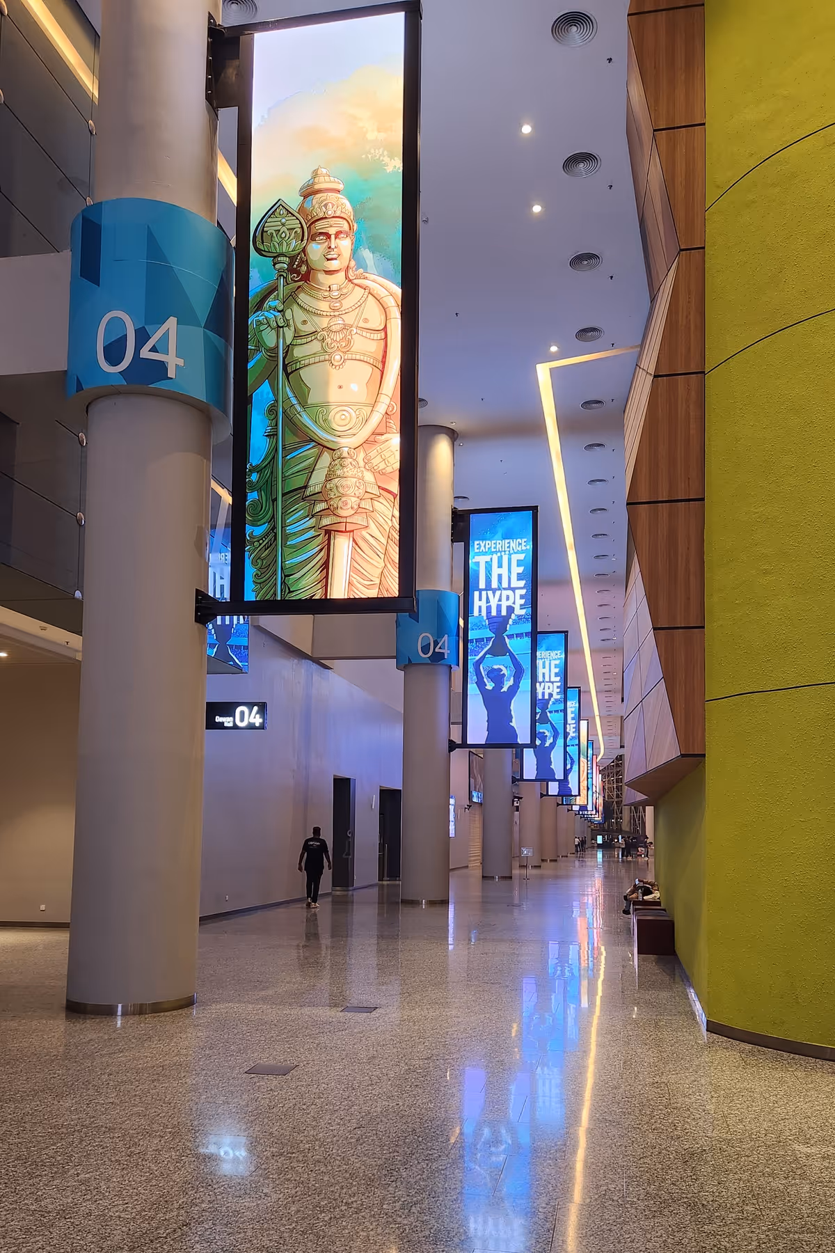 A long hallway with a digital signage screen with an animated Kartikeya.