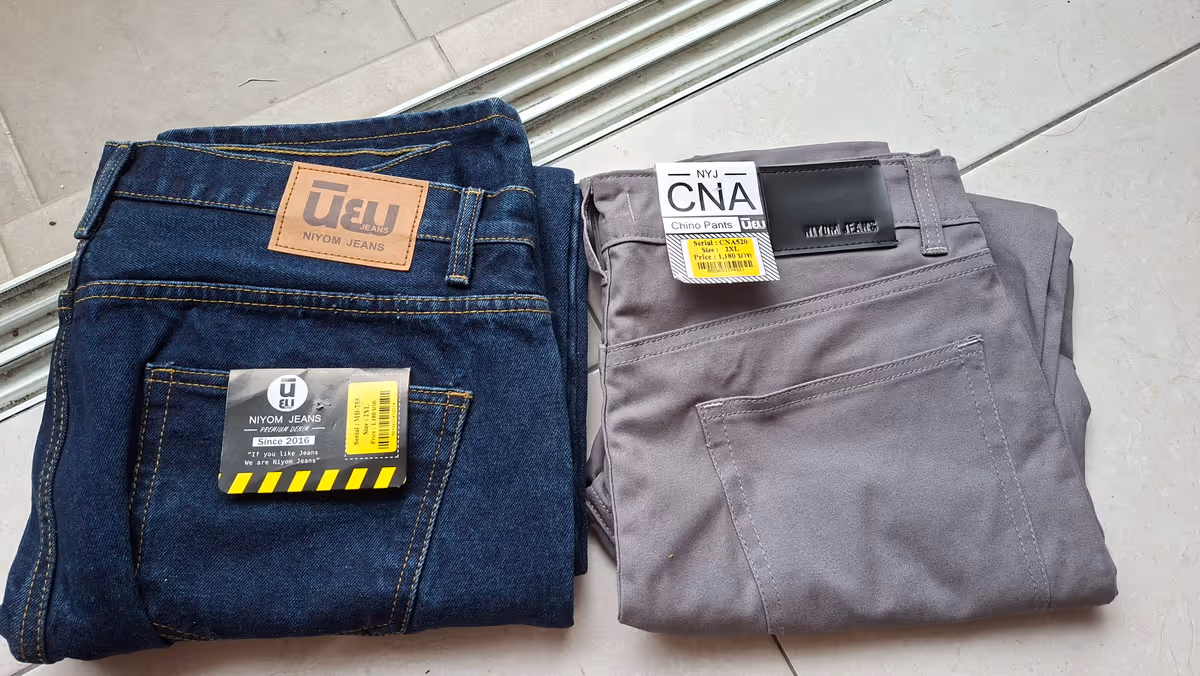 Dark blue jeans and gray chino pants with price tags.