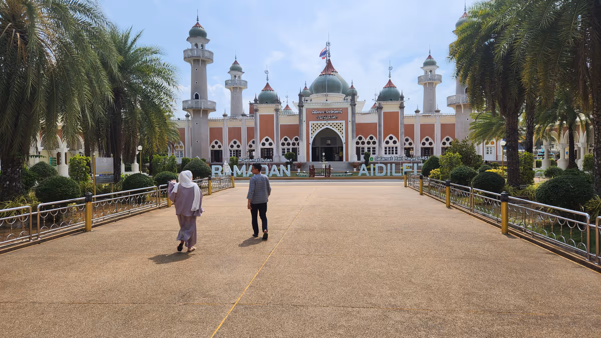 2 people standing in front of a masjid.