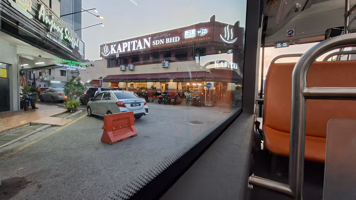 Inside a Penang bus. There is a kapitan restaurant and an orange seat on the right.