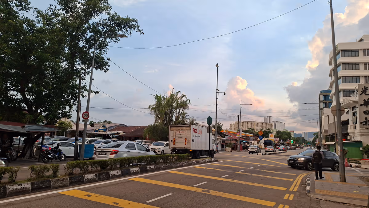 A street with lorries and cars moving along in the evening, under a clear sky