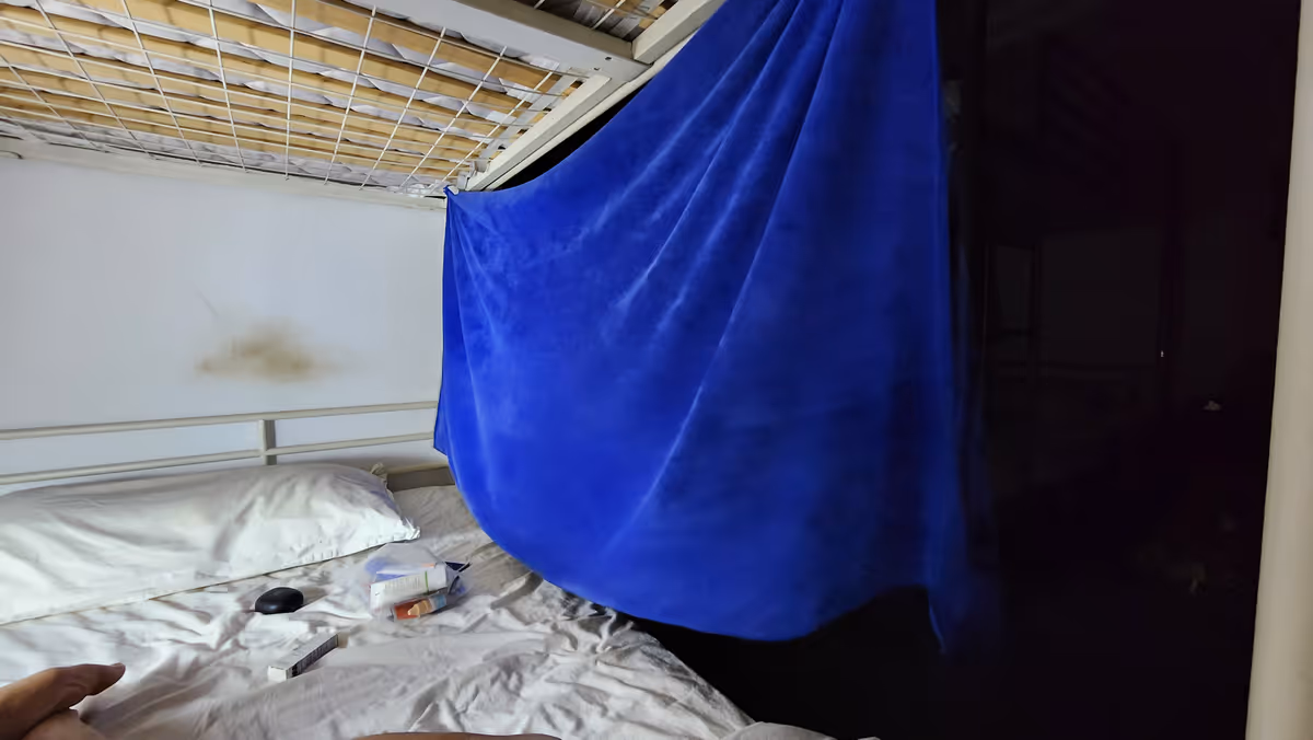 A blue towel hanging the bunk bed.