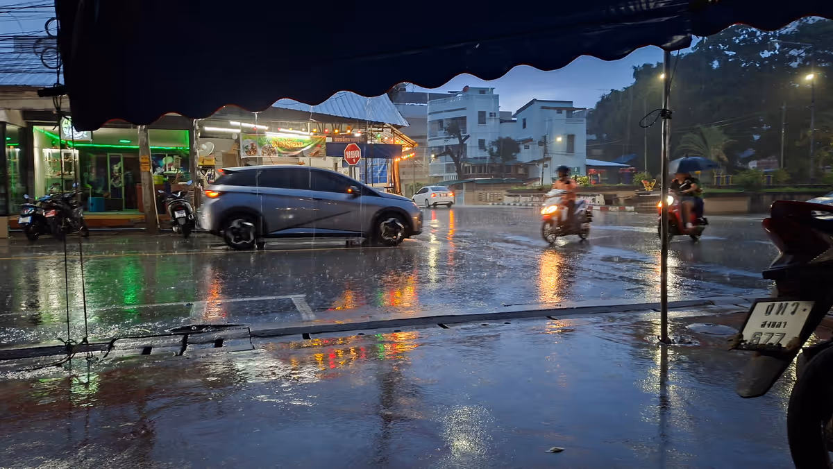 Raining at night. There are many people riding and driving cars and motorcycles through rain.