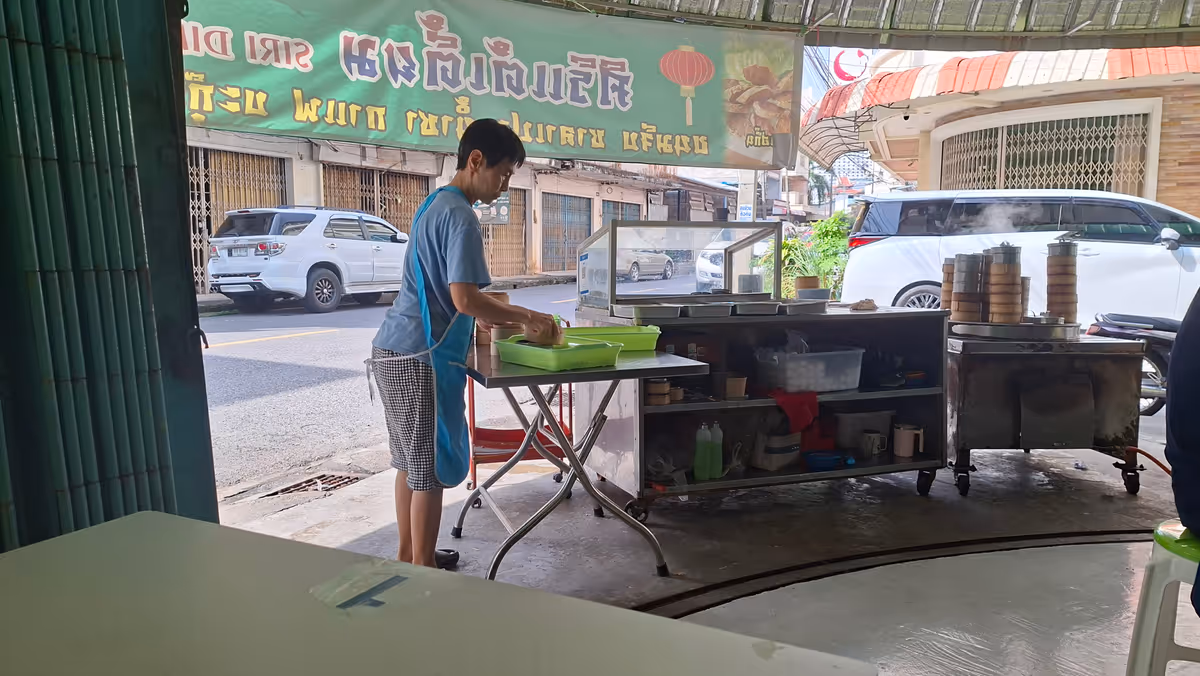 A woman stands near a table and cooking table on the right.