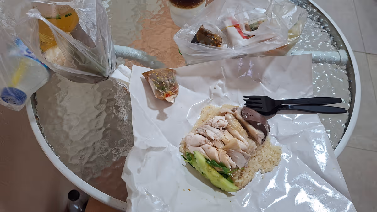 Chicken rice with black utensil and served in a paper plate.