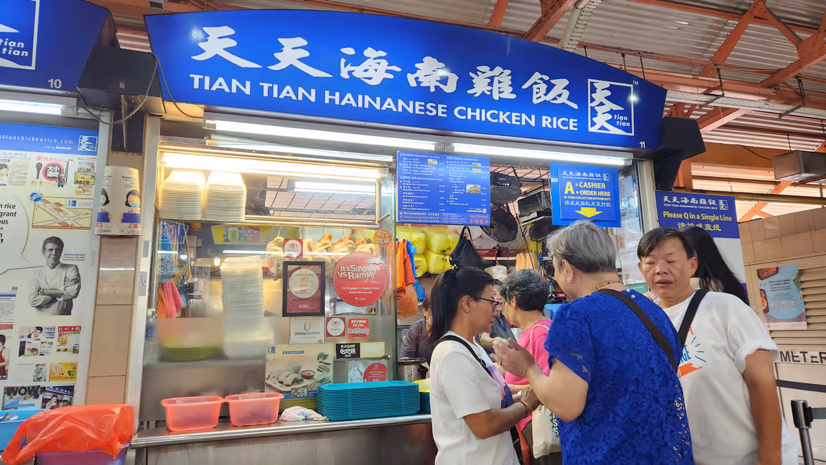 A chicken rice stall with a blue signage in a word Tian Tian hainanese chicken rice.