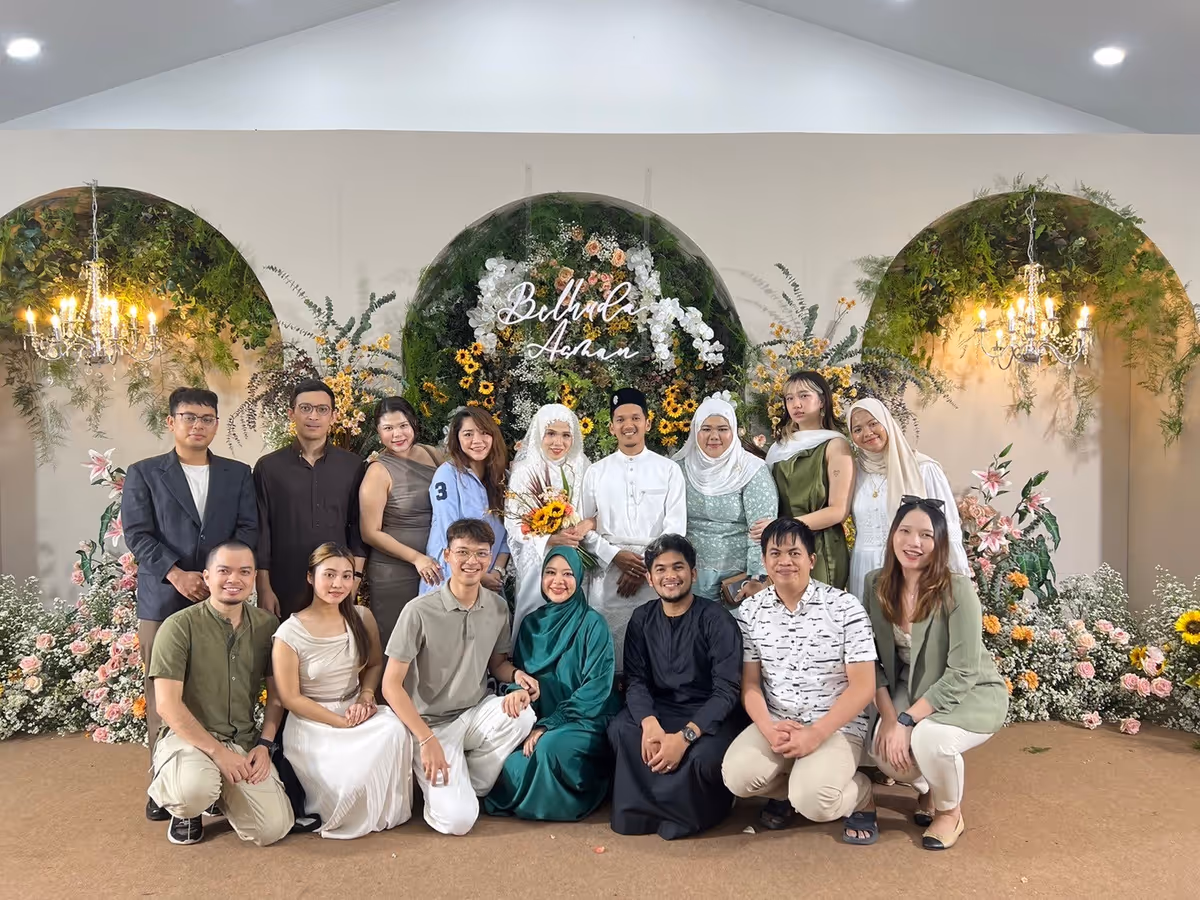 Men and women smiling with bride and groom amoung themselves.