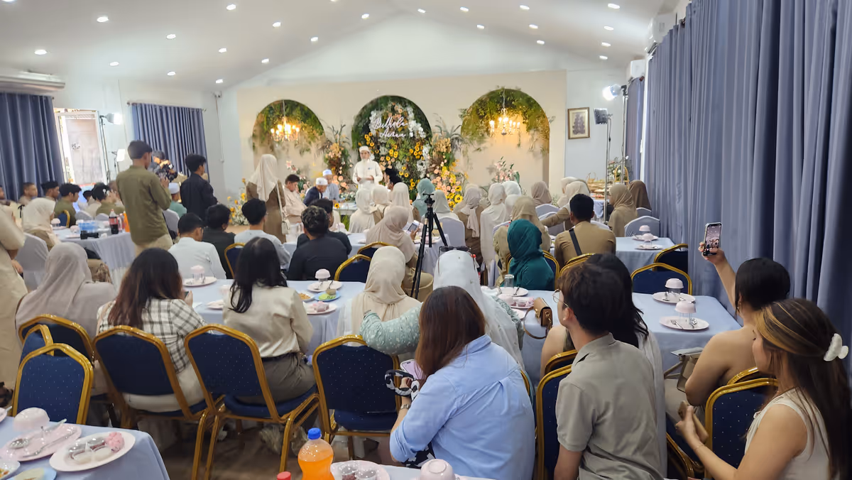 People sit in a room looking at the ceremony.