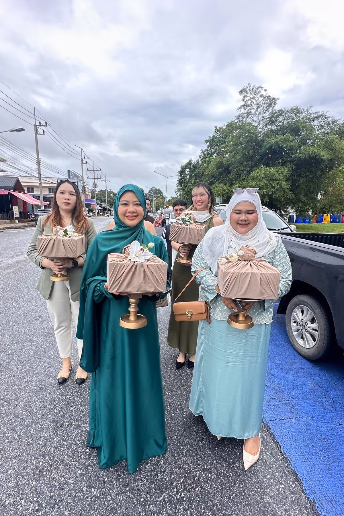 4 women hold gifts in hijab and walking on the street.