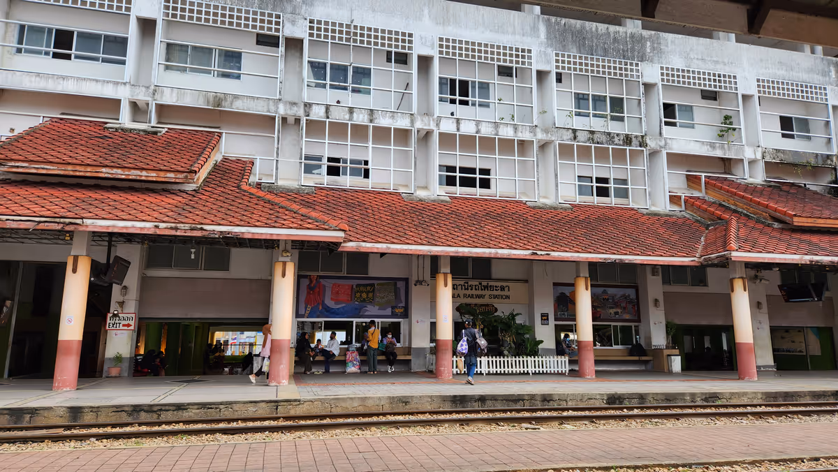 A train station with a building behind the cover.
